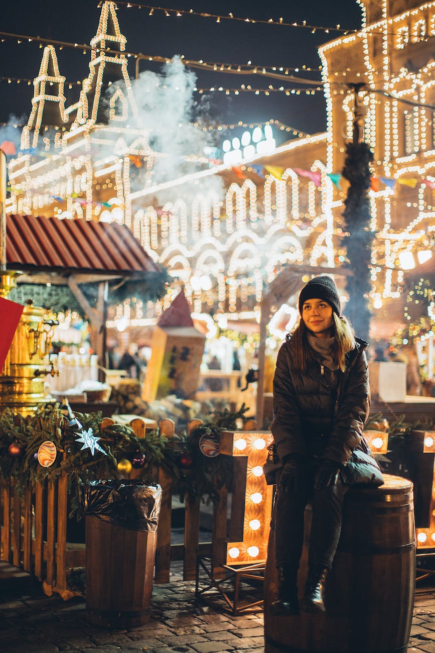 dreamy woman in warm wear on square at new year night