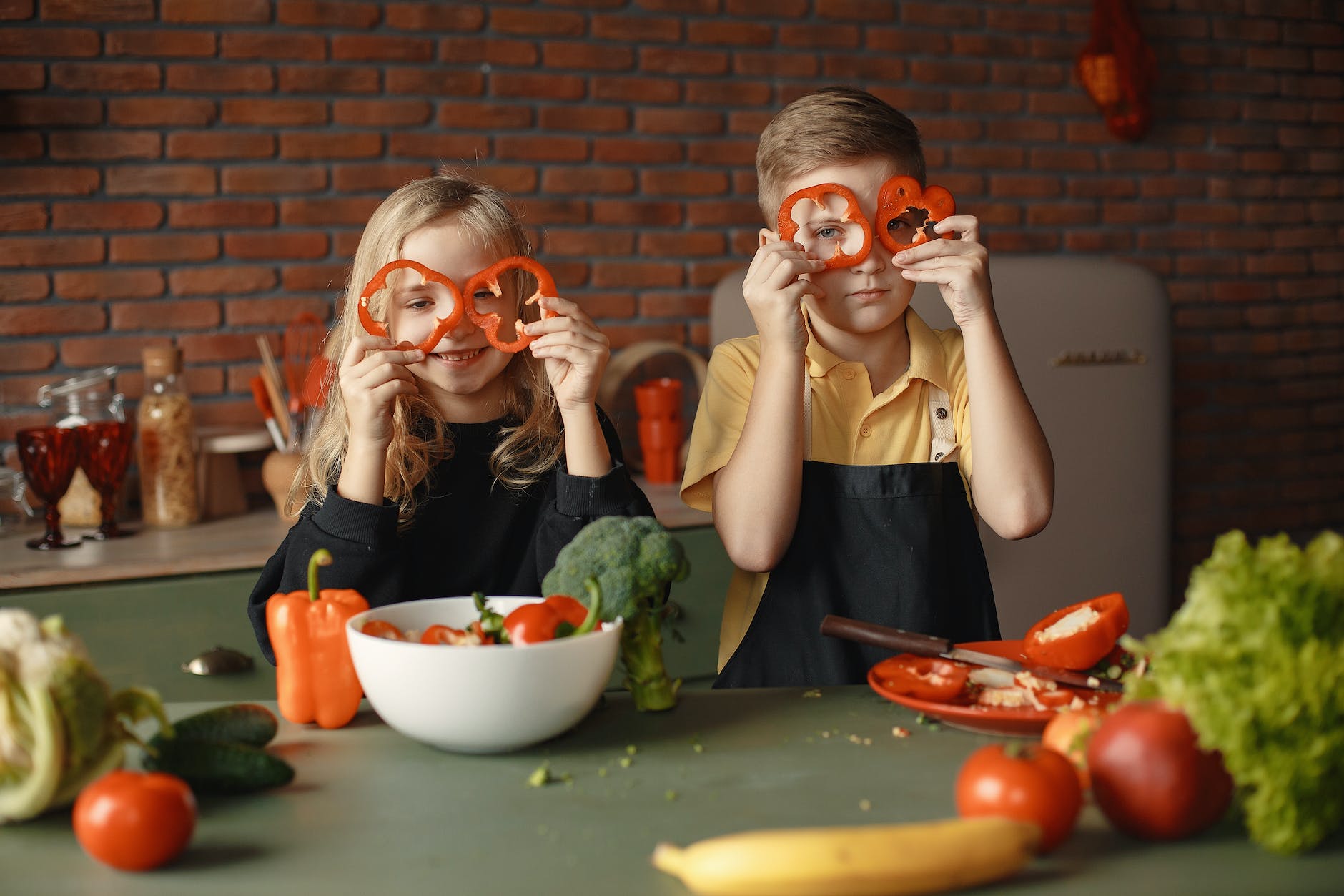 playful little children with assorted vegetables and fruits in loft kitchen